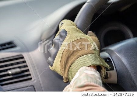 Gloved hand gripping steering wheel inside a modern vehicle interior Gloved hand gripping steering wheel inside a modern vehicle interior 142877139