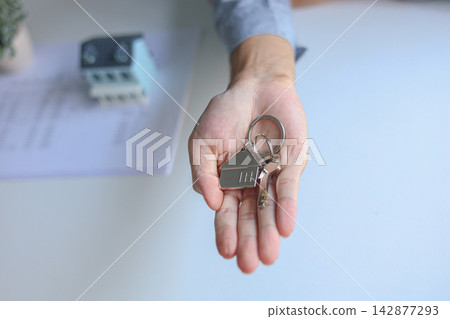 Hand giving house key. Concept for buying, selling, renting or leasing a new home. Hand giving house key. Concept for buying, selling, renting or leasing a new home. 142877293