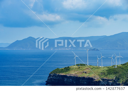 長崎縣生月島的懸崖上排列著一排排用於風力發電的風力渦輪機,以及蔚藍的大海。 長崎縣生月島的懸崖上排列著一排排用於風力發電的風力渦輪機,以及蔚藍的大海。 142877637