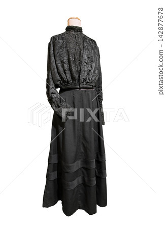 Antique, two-piece walking suit from the turn of the 20th century (Edwardian or late Victorian era), made of black wool and silk, featuring decorative lace and a high collar. 142877678