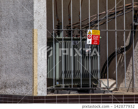 Electrical Transformer and Power Cables behind a Metal Fence Electrical Transformer and Power Cables behind a Metal Fence 142877932