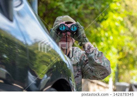 Operative secretly watches a target near a car and gathers intelligence information during a covert mission. Operative secretly watches a target near a car and gathers intelligence information during a covert mission. 142878345