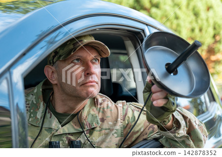 Military operative gathers intelligence and evidence by pointing a sensitive microphone toward a suspected surveillance target. Military operative gathers intelligence and evidence by pointing a sensitive microphone toward a suspected surveillance target. 142878352