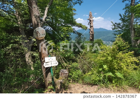 The summit of Mt. Hozan in the Nichiren Alps, Sagamihara City, Kanagawa Prefecture. A mountain marker and hiking trails offering panoramic views of the blue sky and mountain range. The summit of Mt. Hozan in the Nichiren Alps, Sagamihara City, Kanagawa Prefecture. A mountain marker and hiking trails offering panoramic views of the blue sky and mountain range. 142878367