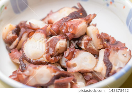 Octopus stir-fried in a frying pan, served in a white bowl—a mouthwatering dish. 142878422