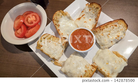 Cheesy Garlic Bread With Marinara Sauce and Sliced Tomatoes on a White Plate 142878500