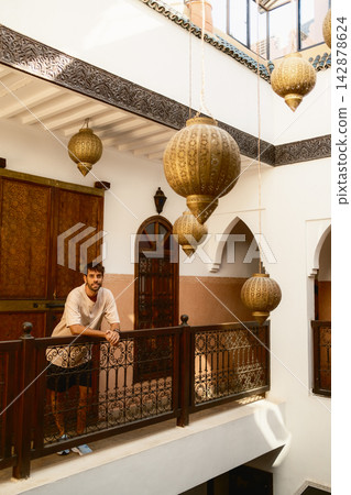 Man Standing on Traditional Riad Balcony With Hanging Lanterns Man Standing on Traditional Riad Balcony With Hanging Lanterns 142878624