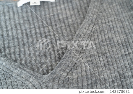 A close-up shot of a gray ribbed knit sweater featuring a V-neck. A close-up shot of a gray ribbed knit sweater featuring a V-neck. 142878681
