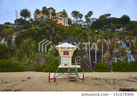 Lifeguard Stand and Palm Trees on Sandy Beach with Clifftop Homes in California Lifeguard Stand and Palm Trees on Sandy Beach with Clifftop Homes in California 142878966
