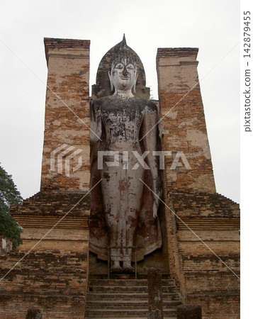 A giant standing Buddha statue at Sukhothai Historical Park (Wat Mahathat) in Thailand. A giant standing Buddha statue at Sukhothai Historical Park (Wat Mahathat) in Thailand. 142879455