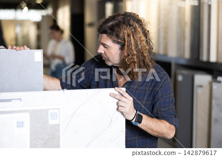 In construction mall,man checks drawing of decorative slabs for suspended ceiling In construction mall,man checks drawing of decorative slabs for suspended ceiling 142879617