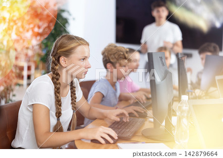Portrait of teen schoolgirl sitting at table in computer class during lesson, smiling at camera. Concept of teenagers and technologies Portrait of teen schoolgirl sitting at table in computer class during lesson, smiling at camera. Concept of teenagers and technologies 142879664