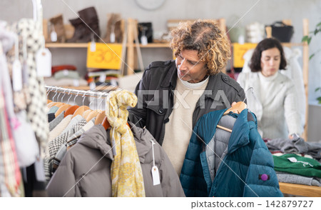 Man search and choose down jacket in store Man search and choose down jacket in store 142879727