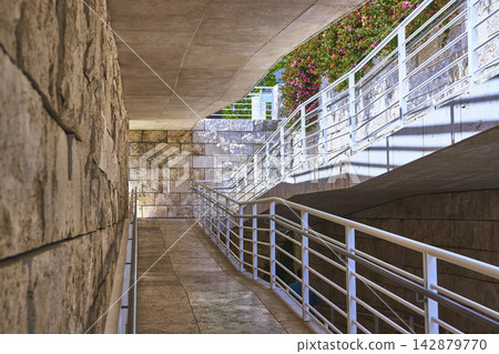 Modern Stone Architecture Walkway with White Railings and Blooming Flowers Modern Stone Architecture Walkway with White Railings and Blooming Flowers 142879770