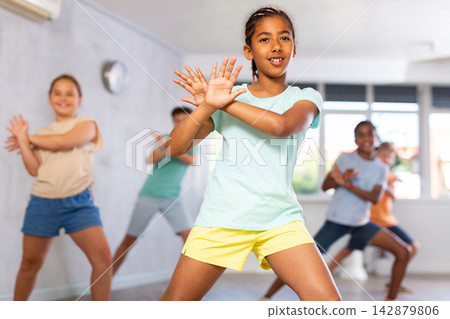 Dancing group of five children practicing new dance in modern studio Dancing group of five children practicing new dance in modern studio 142879806