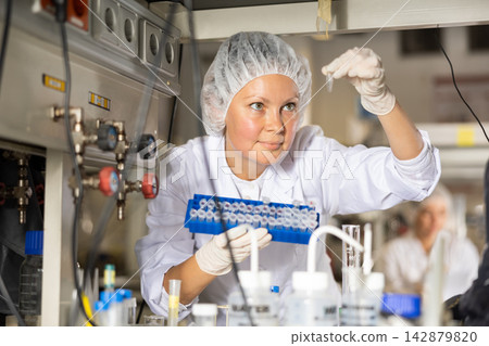Female lab technician working with reagents in test tubes during chemical experiment Female lab technician working with reagents in test tubes during chemical experiment 142879820