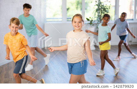 Happy boys and girls enjoying active dance in modern studio Happy boys and girls enjoying active dance in modern studio 142879920