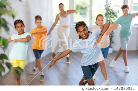 African boy dances vogue in choreographic school, friends and teacher dance in gym blurry background African boy dances vogue in choreographic school, friends and teacher dance in gym blurry background 142880033