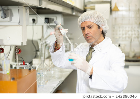 Lab technician working with reagents in test tubes during chemical experiment Lab technician working with reagents in test tubes during chemical experiment 142880040