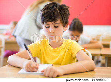 Schoolboy sitting in classroom during lesson in elementary school Schoolboy sitting in classroom during lesson in elementary school 142880056