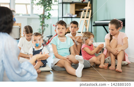 Children sit together and listen to the teacher Children sit together and listen to the teacher 142880103