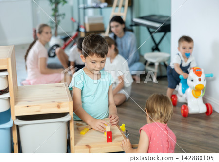 Boy playing with toys in front of children in kindergarten Boy playing with toys in front of children in kindergarten 142880105