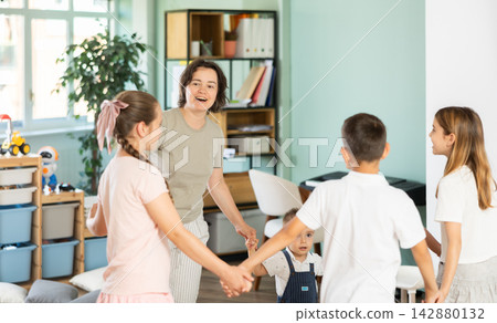 Children holding hands in circle dance in kindergarten Children holding hands in circle dance in kindergarten 142880132