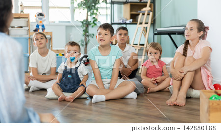 Children sit together and listen to the teacher Children sit together and listen to the teacher 142880188