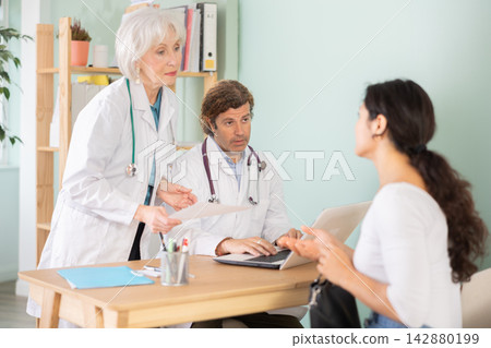 Happy woman discussing medical tests with female and male doctors Happy woman discussing medical tests with female and male doctors 142880199
