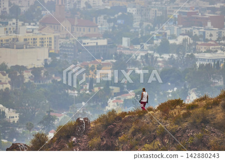 Hiker Overlooks Foggy Los Angeles Skyline from Griffith Park Hillside Hiker Overlooks Foggy Los Angeles Skyline from Griffith Park Hillside 142880243