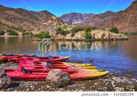 Kayaks on Rocky Shore Beside Colorado River with Desert Mountains and Clear Blue Sky Kayaks on Rocky Shore Beside Colorado River with Desert Mountains and Clear Blue Sky 142880394
