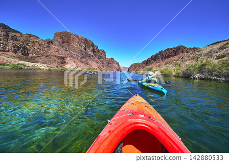Kayaks on Clear Colorado River Water with Red Rock Canyon under Bright Arizona Sky Kayaks on Clear Colorado River Water with Red Rock Canyon under Bright Arizona Sky 142880533