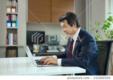 一位老人正在看電腦。 一位老人正在看電腦。 142880569