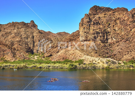 Kayakers on Colorado River with Rocky Cliffs and Desert Landscape in Arizona Kayakers on Colorado River with Rocky Cliffs and Desert Landscape in Arizona 142880779