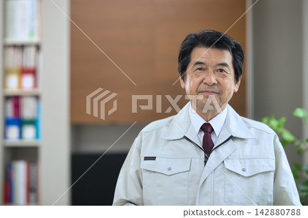一位身穿工作服的老者面帶微笑。 一位身穿工作服的老者面帶微笑。 142880788