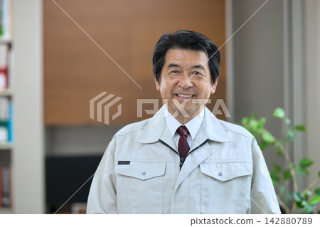 一位身穿工作服的老者面帶微笑。 一位身穿工作服的老者面帶微笑。 142880789