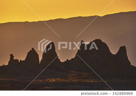 Trona Pinnacles Silhouette at Golden Hour with Sunlit California Desert Hills Trona Pinnacles Silhouette at Golden Hour with Sunlit California Desert Hills 142880969