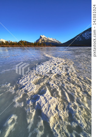 Frozen Lake Texture Winter Pines and Majestic Mountain Under Blue Sky Frozen Lake Texture Winter Pines and Majestic Mountain Under Blue Sky 142881024