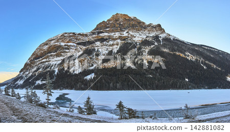 Panoramic Snowy Mountain and Frozen River with Evergreens in Winter Landscape Panoramic Snowy Mountain and Frozen River with Evergreens in Winter Landscape 142881082