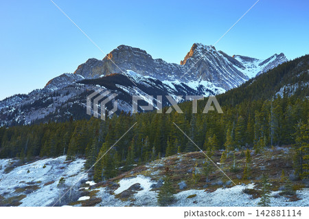 Majestic Snow Capped Rocky Mountains and Pine Forest Winter Landscape at Sunrise Majestic Snow Capped Rocky Mountains and Pine Forest Winter Landscape at Sunrise 142881114