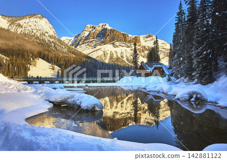 Emerald Lake Lodge and Snowy Pines Reflected in Winter Mountain Landscape Emerald Lake Lodge and Snowy Pines Reflected in Winter Mountain Landscape 142881122