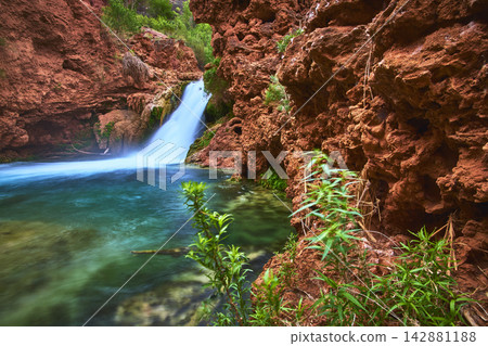 Hidden Waterfall Flowing Into Turquoise Pool With Red Canyon Walls And Green Plants Hidden Waterfall Flowing Into Turquoise Pool With Red Canyon Walls And Green Plants 142881188