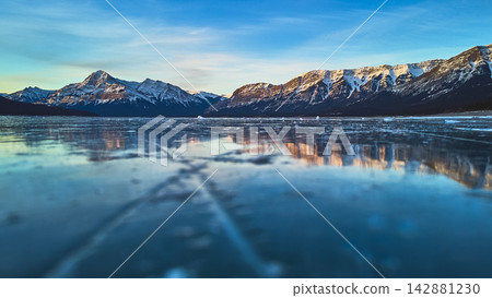 Ground Level Frozen Lake with Snow Capped Mountains and Clear Blue Sky Winter Ground Level Frozen Lake with Snow Capped Mountains and Clear Blue Sky Winter 142881230