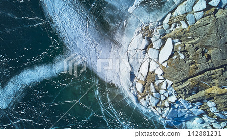 Aerial Frozen Lake Ice Pattern and Rocky Shoreline in Winter Top Down Aerial Frozen Lake Ice Pattern and Rocky Shoreline in Winter Top Down 142881231