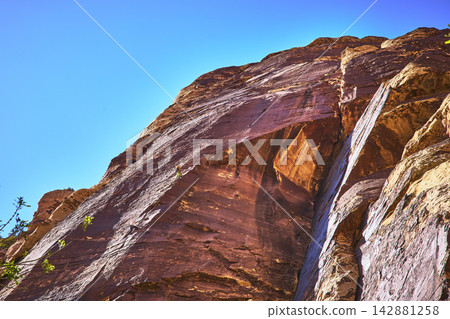 Rock Climber Ascending Red Sandstone Wall in Sunlight at Pine Creek Nevada 142881258