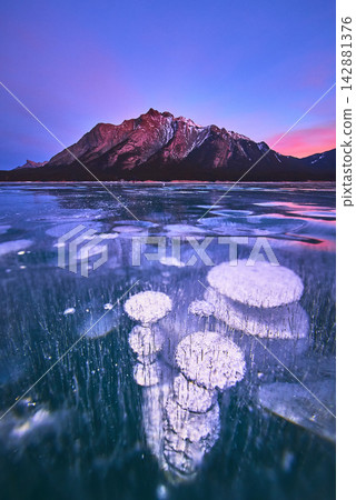 Frozen Methane Bubbles and Majestic Mountain at Winter Sunset on Icy Lake Frozen Methane Bubbles and Majestic Mountain at Winter Sunset on Icy Lake 142881376