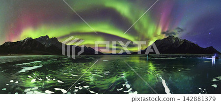 Panorama Northern Lights Over Frozen Lake With Ice Bubbles And Winter Mountains Panorama Northern Lights Over Frozen Lake With Ice Bubbles And Winter Mountains 142881379