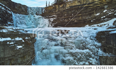 Frozen Waterfall and Rocky Canyon with Snowy Cliffs in Winter Aerial Frozen Waterfall and Rocky Canyon with Snowy Cliffs in Winter Aerial 142881386