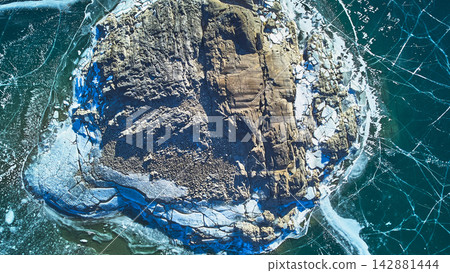 Aerial Frozen Rocky Outcrop with Cracked Ice Patterns on Winter Lake Top Down Aerial Frozen Rocky Outcrop with Cracked Ice Patterns on Winter Lake Top Down 142881444