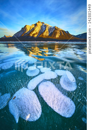 Frozen Methane Bubbles Under Clear Ice and Sunlit Mountain Winter Landscape Frozen Methane Bubbles Under Clear Ice and Sunlit Mountain Winter Landscape 142881449